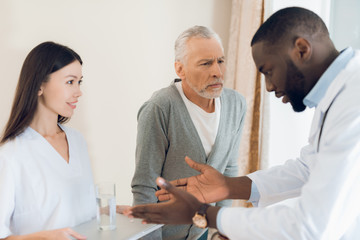 Fototapeta premium The doctor tells the nurse how an elderly male patient should take pills.