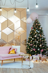 the room decorated by Christmas. A pink sofa and a big fir-tree with toys, spheres, garlands and gifts.