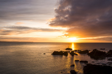 sunrise at hannafore point with beautiful golden sky and rocks in sea, cornwall, uk