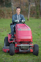Fototapeta premium young gardener on a lawn tractor
