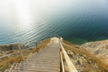 A steep descent down the long metal stairs to the shore of the blue sea