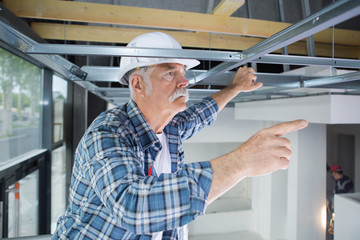 senior man working on ceiling panels