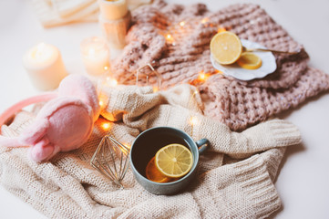 Cozy winter morning at home. Hot tea with lemon, knitted sweaters and modern interior details. Flat lay still life composition.