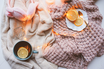Cozy winter morning at home. Hot tea with lemon, knitted sweaters and modern interior details. Flat lay still life composition.