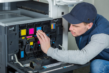 Man checking ink cartridges in photocopier