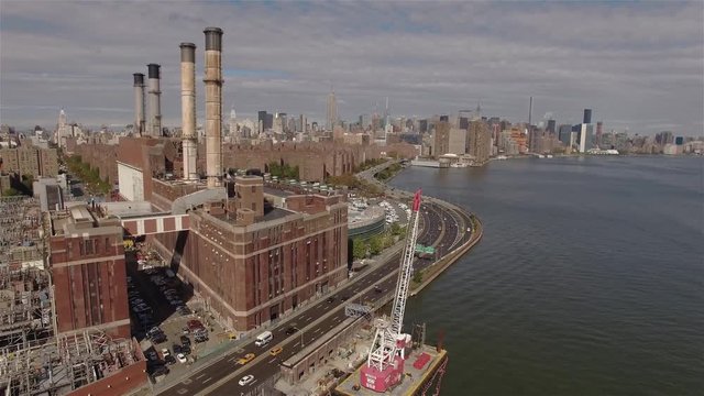 Aerial shot of a power station in New York City. Camera is flying left filming the power station and East Rive and Midtown Manhattan.