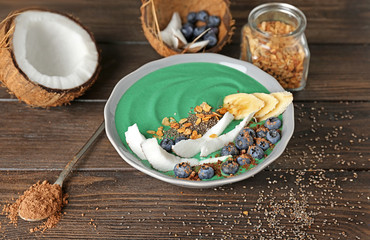 Bowl with green spirulina smoothie on table. Healthy vegan food concept