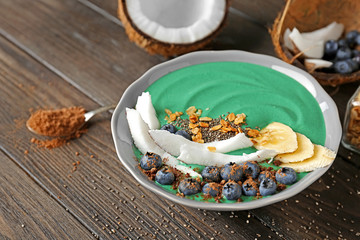 Bowl with green spirulina smoothie on table. Healthy vegan food concept
