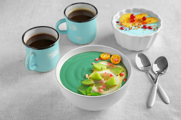 Bowl with green spirulina smoothie on table. Healthy vegan food concept