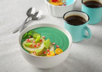 Bowl with green spirulina smoothie on table. Healthy vegan food concept