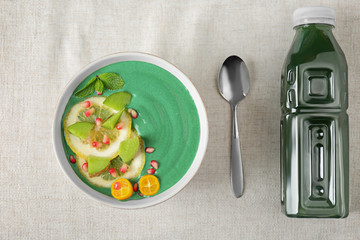 Bowl with green spirulina smoothie on table. Healthy vegan food concept