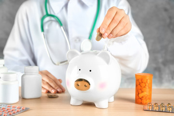 Doctor putting coin into piggy bank. Health care concept