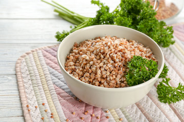 Bowl with cooked buckwheat on table