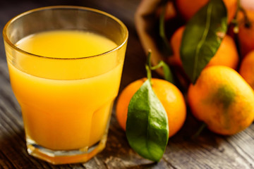 Glass of fresh juice and mandarins on table
