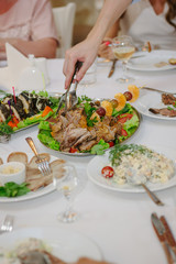 Hands with tongs lets pieces of christmas turkey for eating.