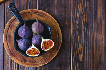 Fresh and ripe figs inside frying pan over wooden table.