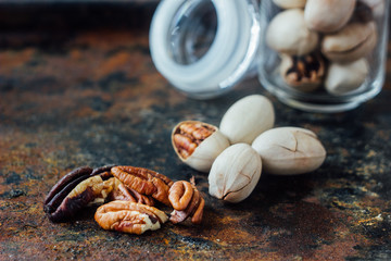 Pecan nuts inside glass jar on rustic surface.