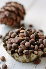 Pine or cedar nuts in a metalic bowl on the white wooden table.