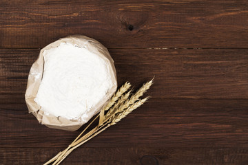 Paper package of wheat flour on a wooden background. Top view, copy space. Food background