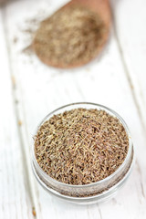 Cumin or caraway spice in a glass jar over white wooden background.