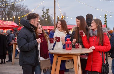 Five young people drinking mulled wine at Christmas market