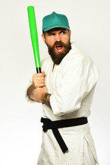 Karate man with greedy face holds green baseball bat.