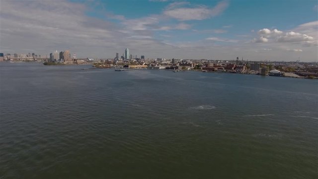 Aerial real time panoramic shot of Midtown Manhattan. Camera is hovering in the air above East River in New York city and filming of floating white ferry which is going toward Downtown.