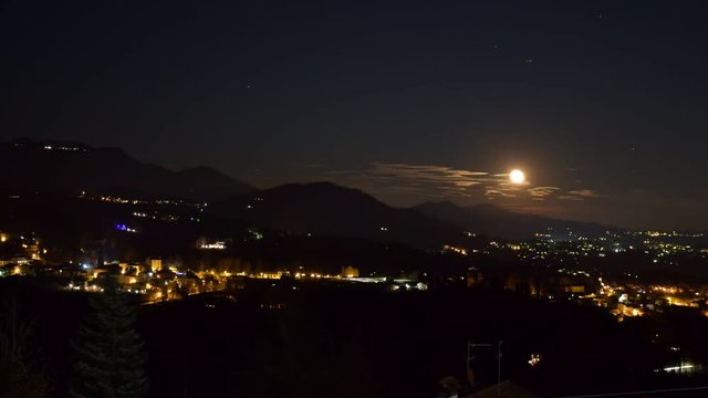 timelaps del sorgere della luna piena,sopra il paesino illuminato