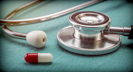 Red and white capsule next to a stethoscope, conceptual image