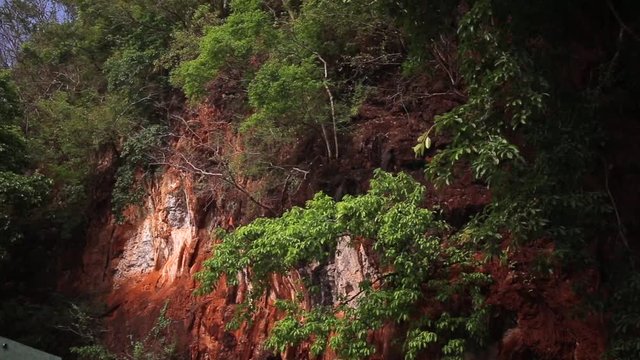 Red horizontal striations in sandstone rock cliff wall. Thailand.