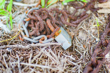 Lock and rusty chain on the ground