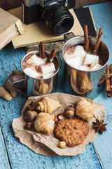 Metal cups with cacao and marshmallow and different cookies