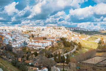 Aerial panoramic view of Ronda, tradational white houses with tile roofs on the hill and its surroundings, one of most famous white villages (pueblos blancos) in Malaga province, Andalusia, Spain.