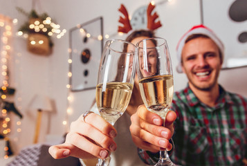 Merry Christmas and Happy New Year! Happy couple in Santa caps toasting with champagne at midnight.