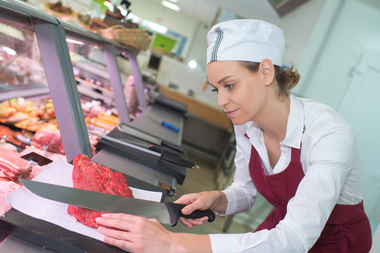 female butcher cutting a meat