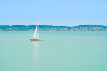 A view from a ship to bright Balaton lake water and a white yacht on sunny summer day, Hungary.
