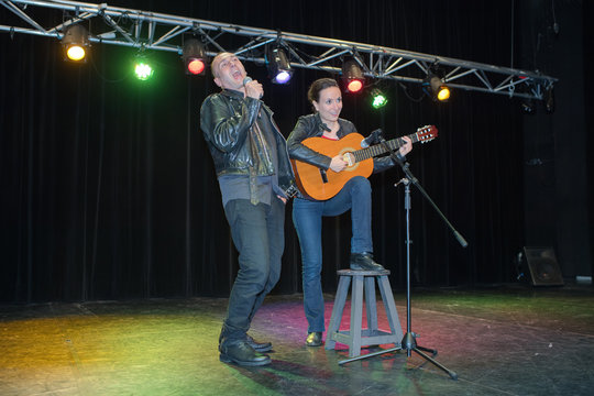 Couple singing and playing guitar on stage