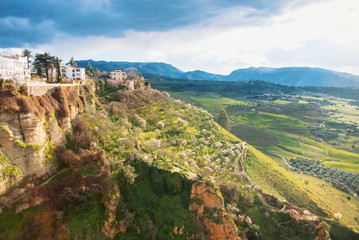 A view to El Tajo Gorge Canyon, traditional andalusian houses at the cliff and a lot of flowering almond trees on the slope at famous white village Ronda in Malaga province, Andalusia, Spain.
