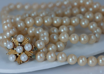 Vintage pearls with gold flowered clasp and clasp on earrings with white background.