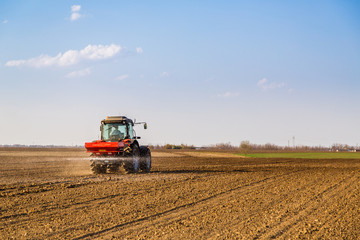 Fototapeta premium Farmer fertilizing arable land with nitrogen, phosphorus, potassium fertilizer