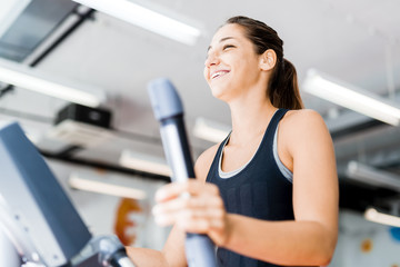 Beautiful young lady using the elliptical trainer