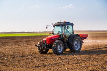 Naklejka premium Farmer fertilizing arable land with nitrogen, phosphorus, potassium fertilizer