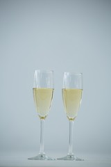 Two champagne flutes against white background