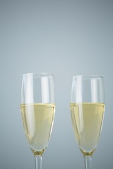 Two champagne flutes against white background