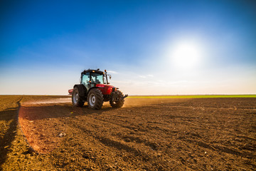 Obraz premium Farmer fertilizing arable land with nitrogen, phosphorus, potassium fertilizer