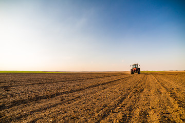 Fototapeta premium Farmer fertilizing arable land with nitrogen, phosphorus, potassium fertilizer