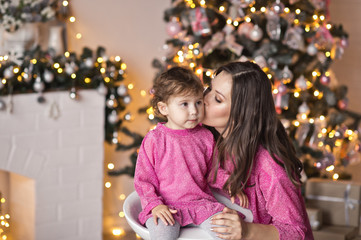 Portrait of mother with daughter on the Christmas tree in sparkling lights
