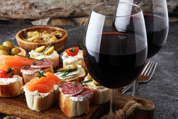 Italian antipasti wine snacks set. Cheese variety, Mediterranean olives, pickles, salami, salmon, tomatoes, artichokes and wine in glasses. Spanish tapas