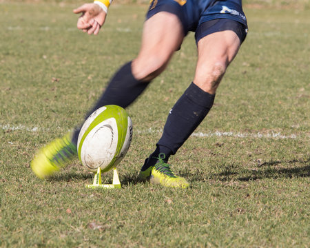 Legs of rugby player kicking ball