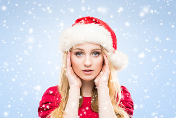 Attractive and beautiful girl in Christmas hat over winter background with snowflakes.